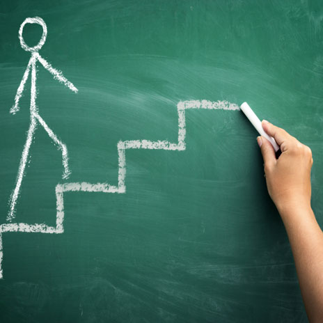 Hand drawing stick figure climbing stairs on chalkboard