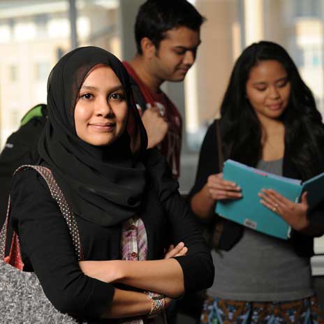 Three students in academic setting with books