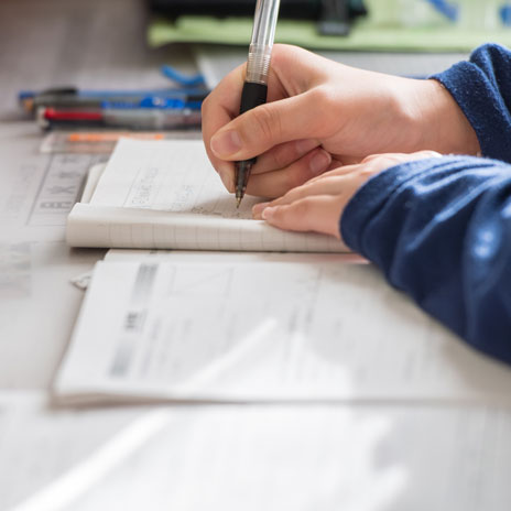 Close-up of a person filling out an application form at a desk with documents and stationery