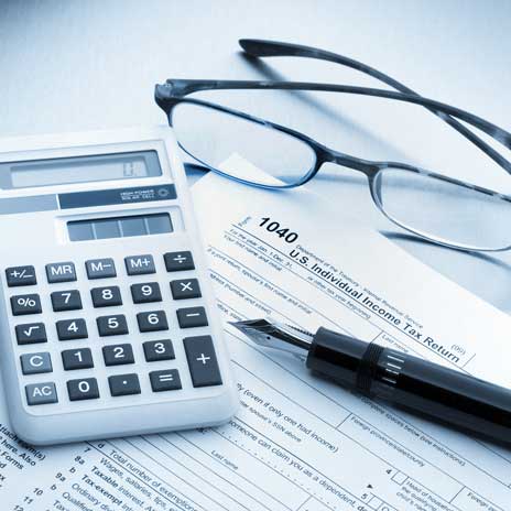 1040 tax form with calculator, glasses, and pen.