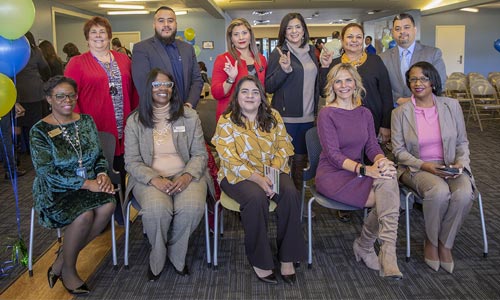 Group photo of eleven people at the Bilingual Education Launch event, with balloons and chairs in the background.