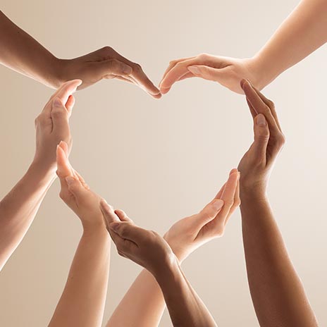 Hands of diverse skin tones forming a heart shape