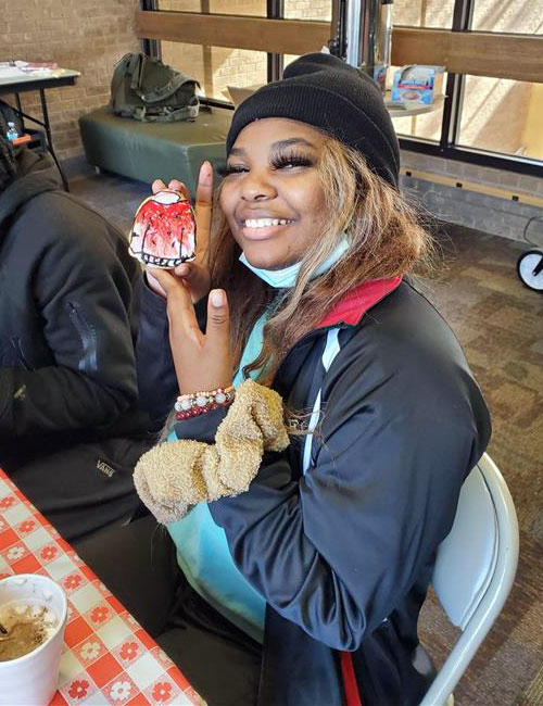 Student holds a homemade cookie with frosting