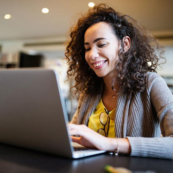 female girl smiling and typing on laptop
