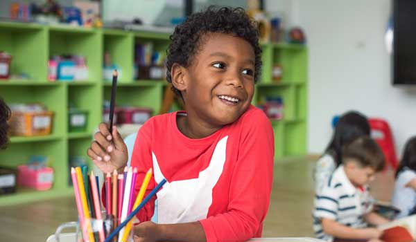 Preschool child coloring and smiling