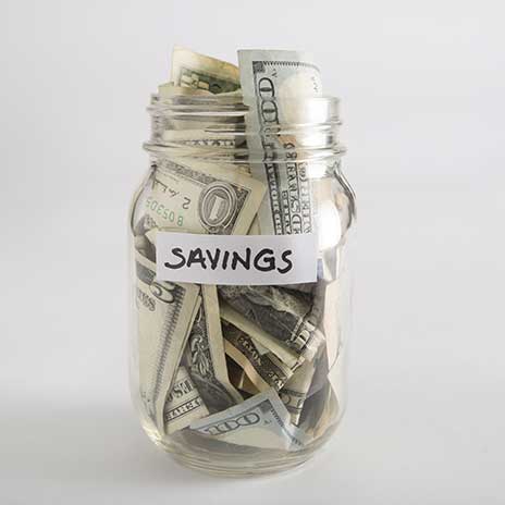 Glass jar labeled 'Savings' filled with U.S. dollar bills, representing financial savings and budgetin