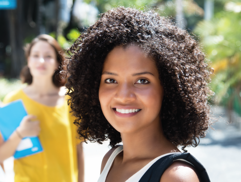 two female students smiling with their backpacks and notebooks