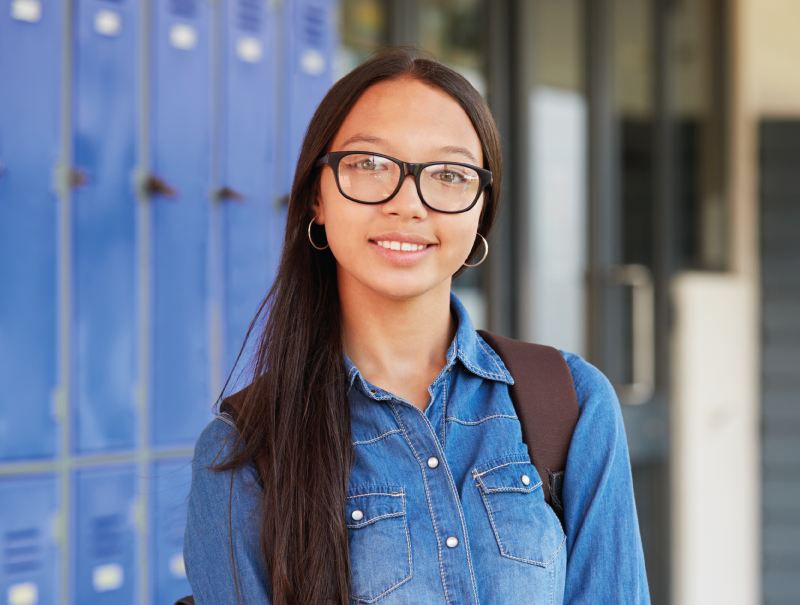 a portrait photo of a female student smiling in front of school lockers