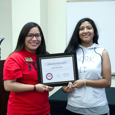 Two students holding a certificate of excellence