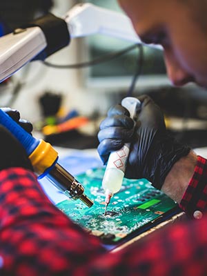 A worker soldering a mother board