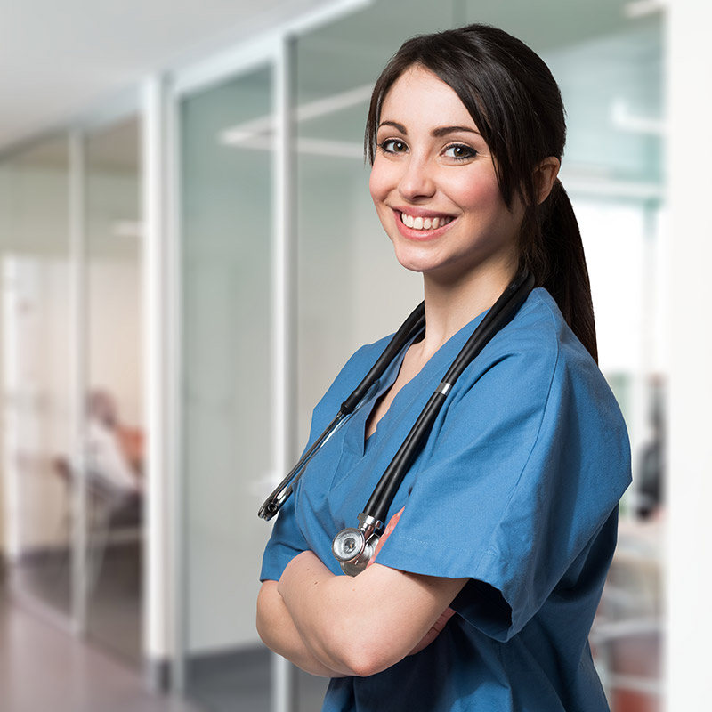 female nurse standing and smiling in hospital hallway