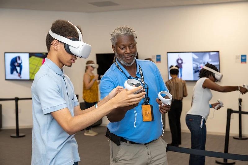 A student wears a VR headset while an instructor provides directions
