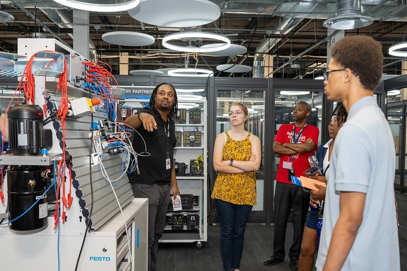 Students watch as an instructor shows how manufacturing circuits work