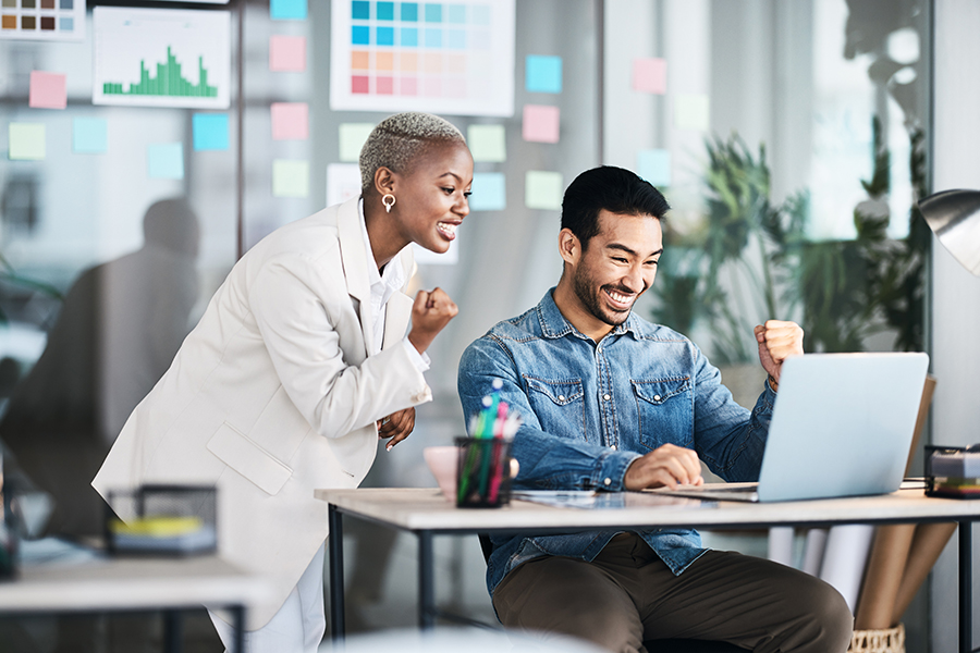 Two co-workers celebrating at a laptop