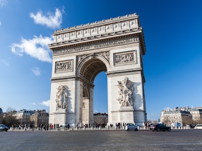 The Arc de Triomphe in Paris under a clear blue sky, with detailed carvings