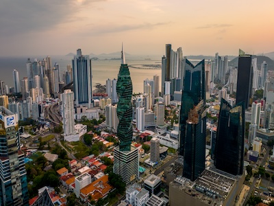 Aerial view of the Panama skyline at sunset, featuring tall, uniquely designed skyscrapers and a bay in the background
