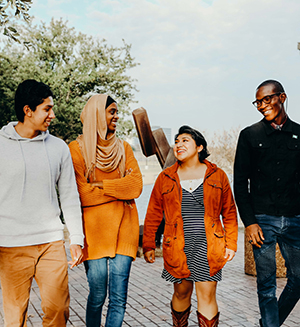 A group of four friends walking outdoors, smiling and chatting
