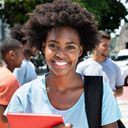 A smiling student with curly hair holds a red tablet outdoors