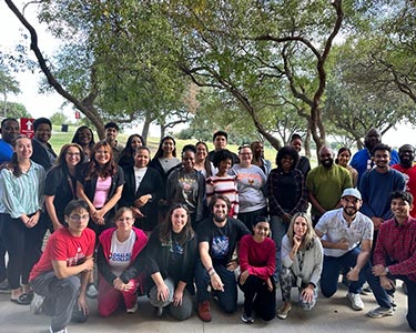 Student Ambassadors pose for a group photo under a large tree during their 2024 training