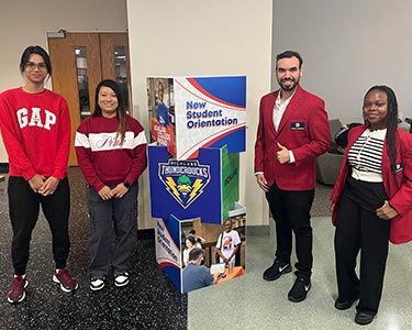 Student Ambassadors stand near signage for NSO at Richland