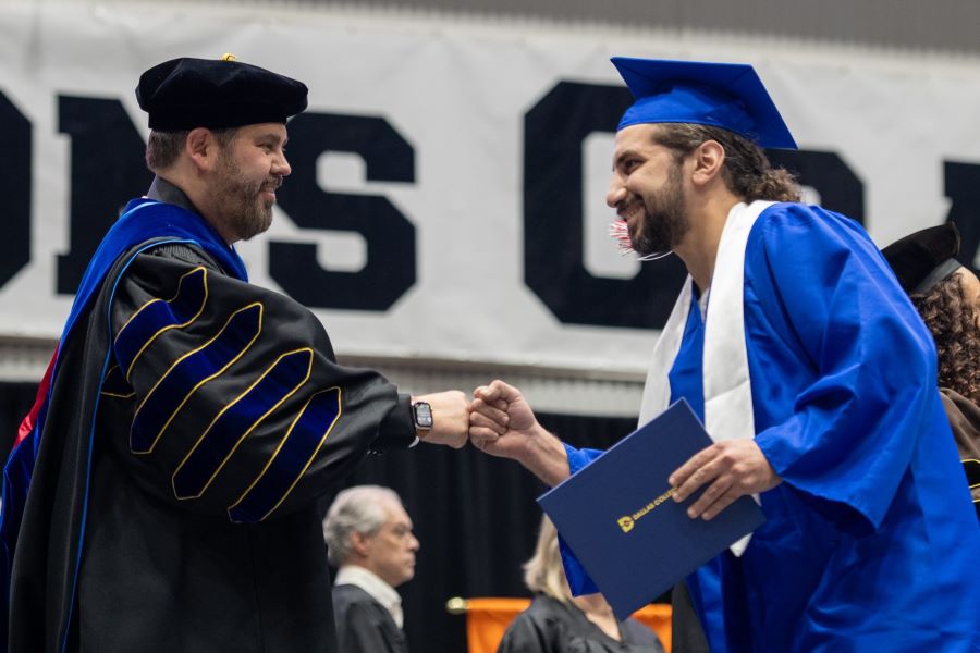 A student gives Dr. Lonon a fist bump as he crosses the stage with his diploma