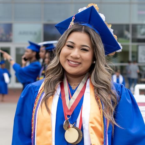 A Phi Theta Kappa stands outside the arena wearing her regalia