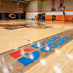 A wide shot of the Cedar Valley gym with the Dallas College logo seen in the foreground across the gym floor.