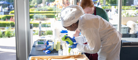 A culinary student decorates a cake at an outdoor event