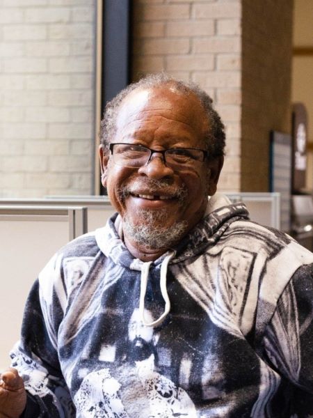 A lifelong learning student sits in the hallway at Eastfield at a study spot and turns to smile at the camera