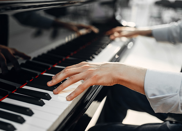 Close up of two hands playing a grand piano