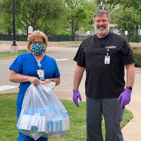 Eastfield's Dr. Jess Kelly, Executive Dean-STEM Division, presents gloves to Lisa Fox, DRMC Director of Emergency Room Operations.