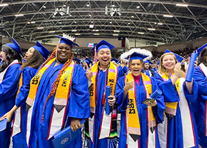 Several inaugural recipients of the bachelor's degree in Education stand wearing their caps and gowns