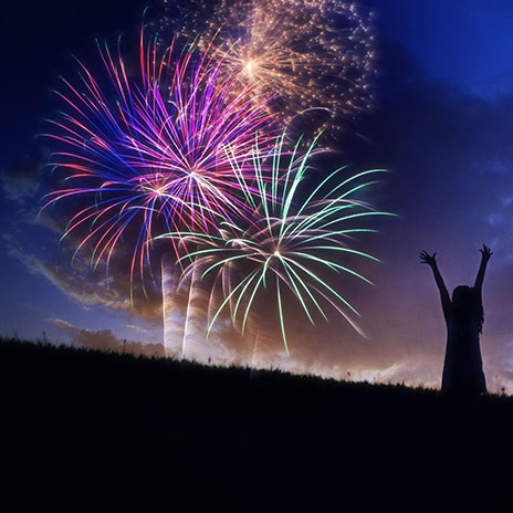 fireworks display in the air at night with a silhouette of a child watching