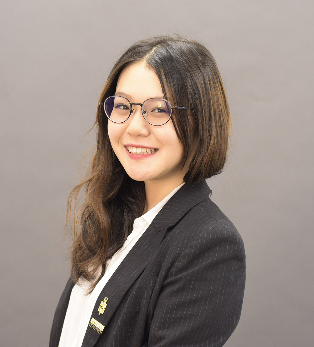 Smiling Asian female with long brown hair and glasses posing for the camera