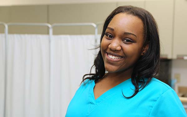 A nurse stands in a hospital room smiling
