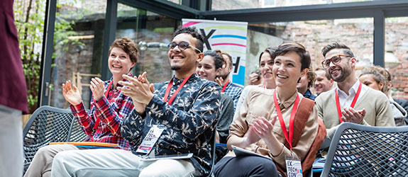 student clapping and smiling at conference