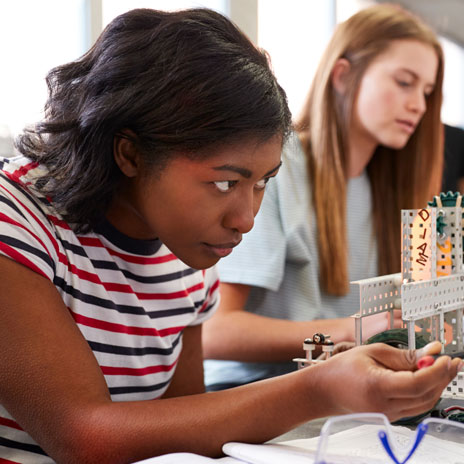 Two college students tinker with a science project in laboratory setting