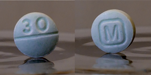 Photo of blue round pills, one with “30” on it and one with the “M” in a square
