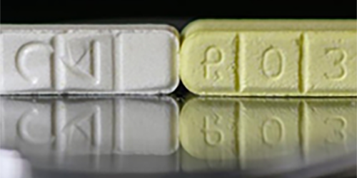 Photo of long white pill next to long yellow pill