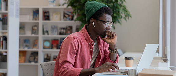 male student typing on laptop and listening to headphones