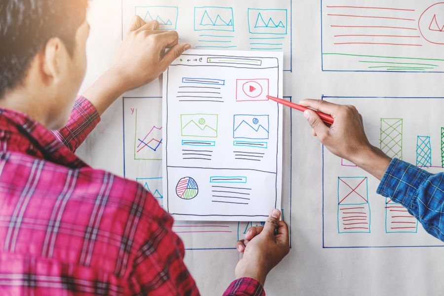 Web designers look at potential wireframes on a whiteboard