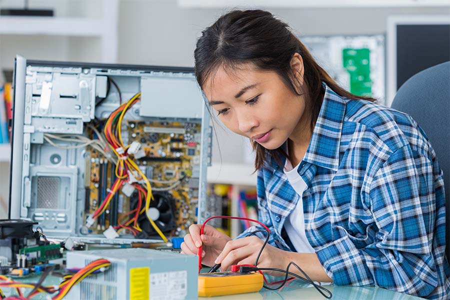 Young woman tests wiring inside a computer