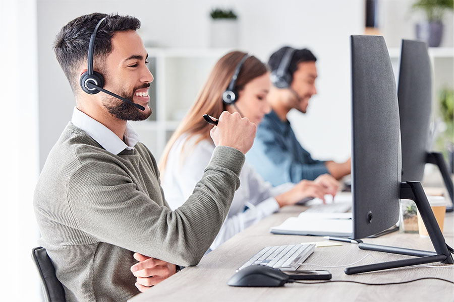 Call center representative with headset smiling at a computer