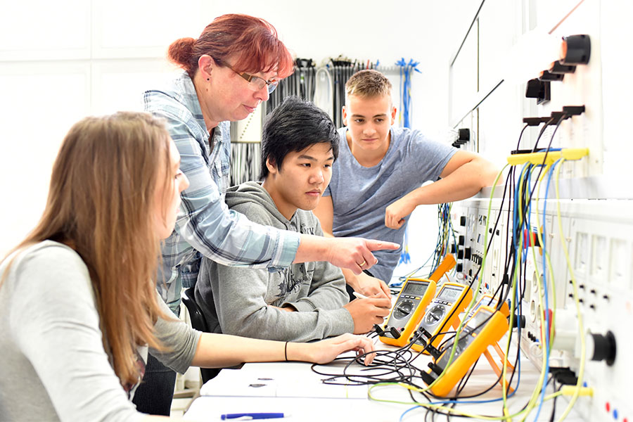 Students working with an electrical engineering instructor.